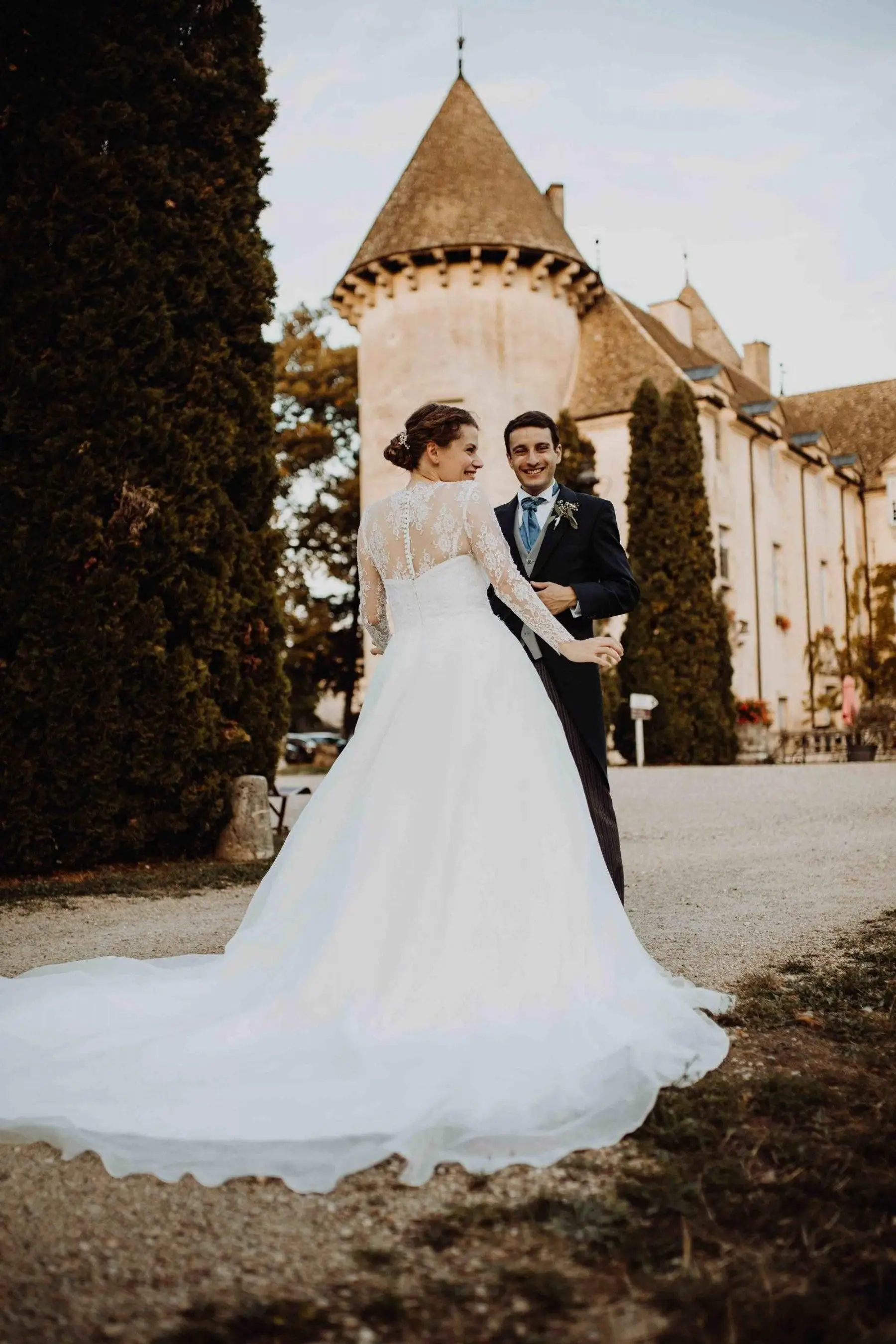 A bride and groom holding hands in front of a turreted French château