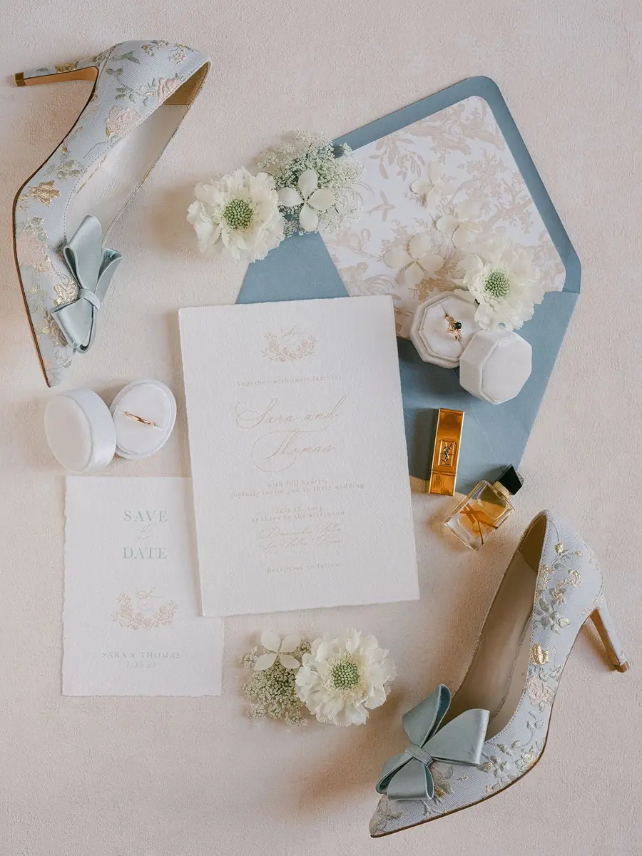 Wedding stationery, rings and embroidered heels styled as a flat-lay