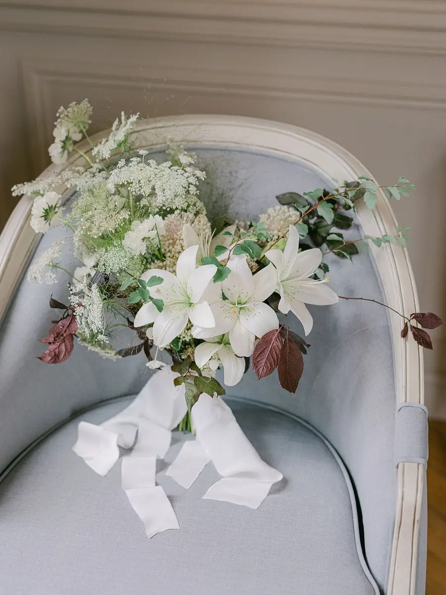 White lily and Queen Anne's lace bridal bouquet resting on a pale blue chair